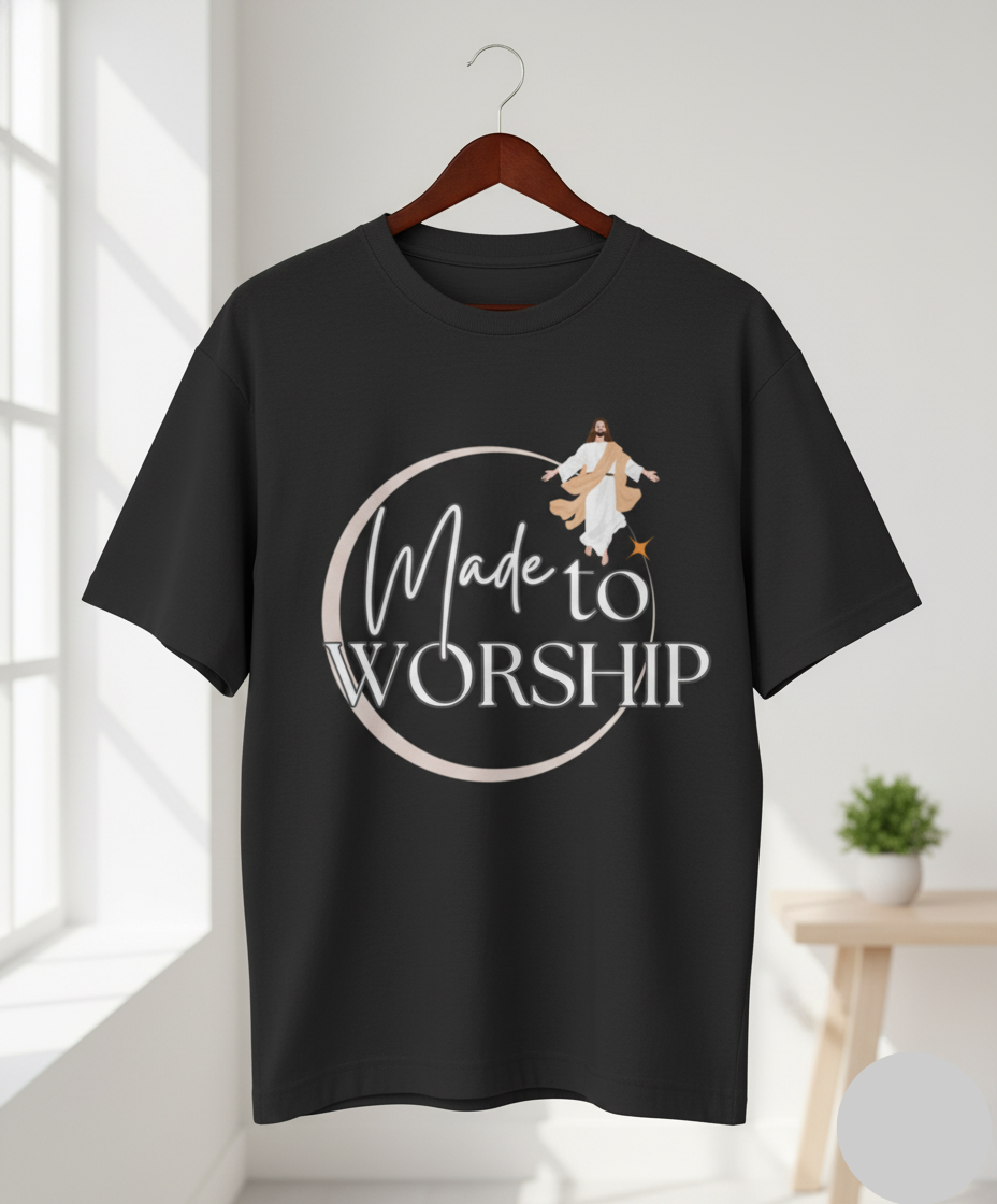Black t-shirt with 'Made to Worship' design on a hanger in a bright room.